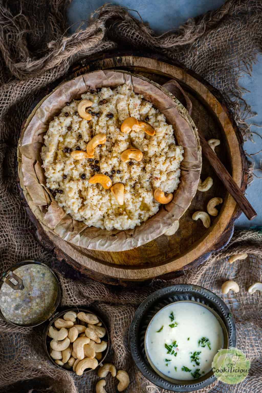 Instant Pot Ven Pongal garnished with cashews, and black pepper served in a rustic bowl.