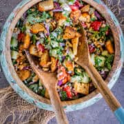 2 salad spoons tossing Cucumber Tomato and Feta Salad in a bowl.