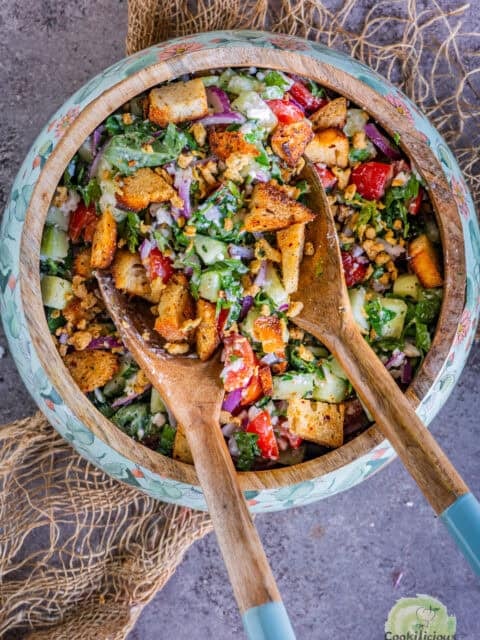 2 salad spoons tossing Cucumber Tomato and Feta Salad in a bowl.