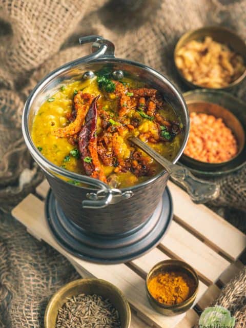 Dal Tadka served in a brass bucket with a spoon in it