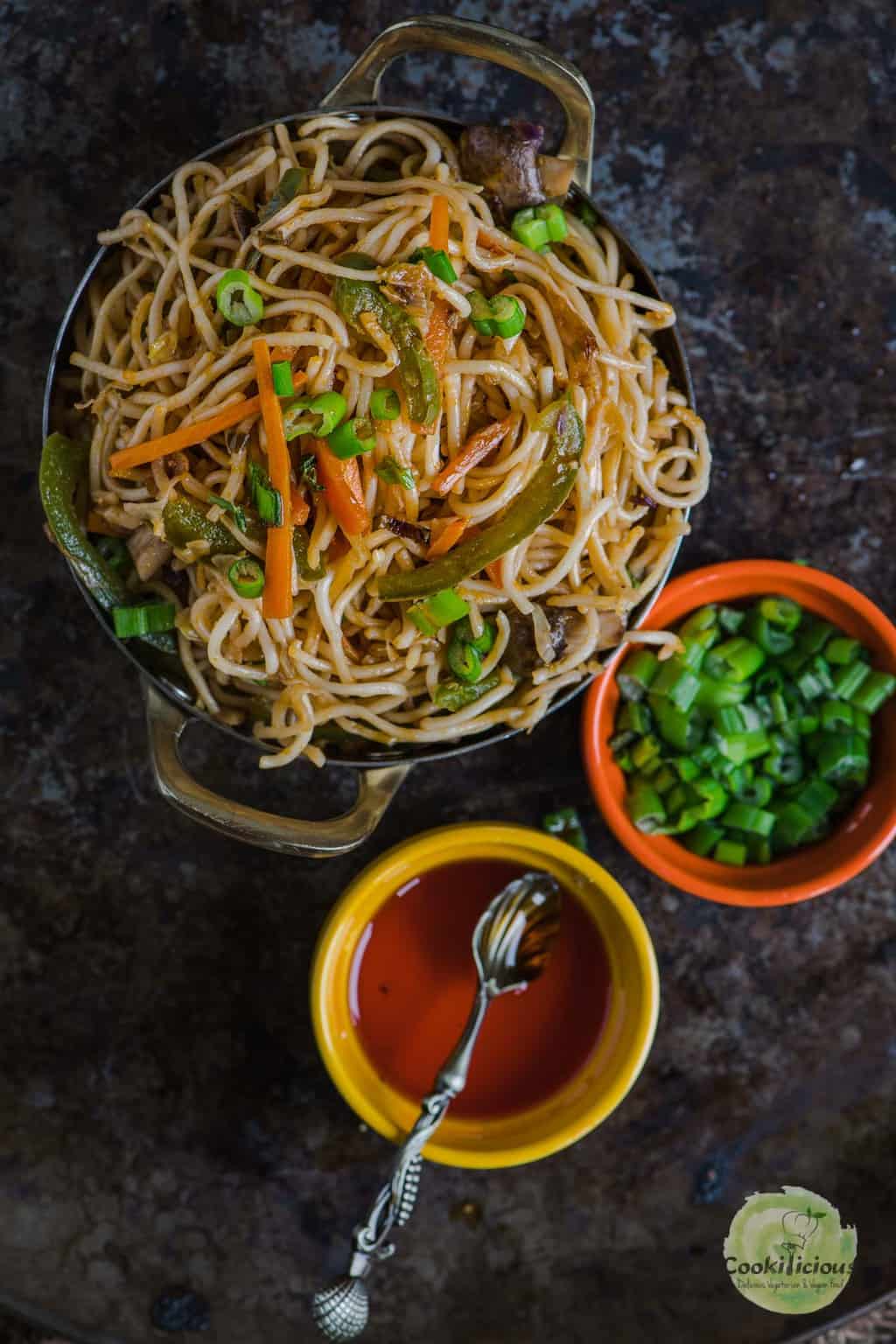 Veg Hakka Noodles served in a bowl with chili sauce and scallions on the side
