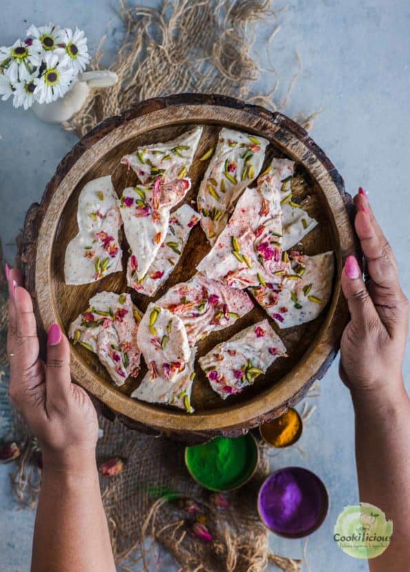 a set of hands holding a platter filled with White Chocolate Thandai Bark