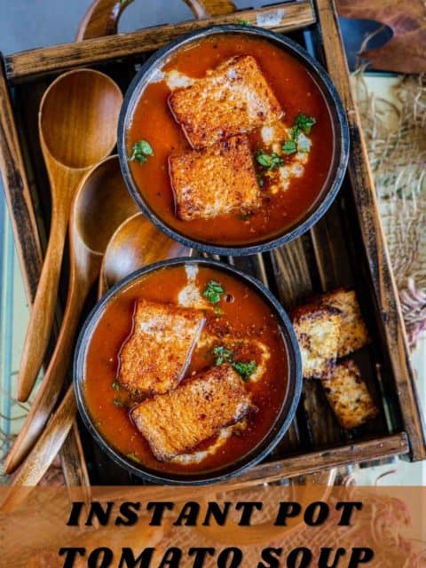 2 bowls of vegan tomato soup served in a wooden tray and text at the bottom
