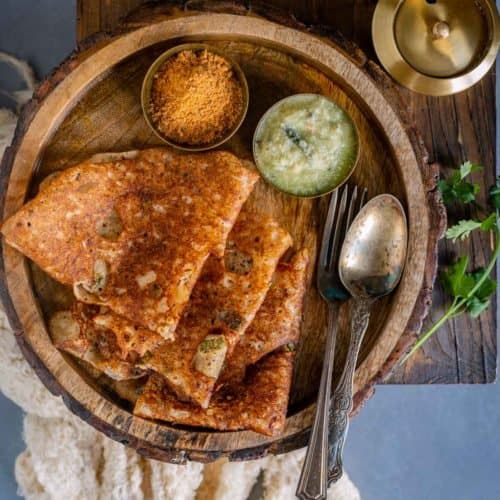 3 folded Onion Rava Dosa served in a plate with chutneys