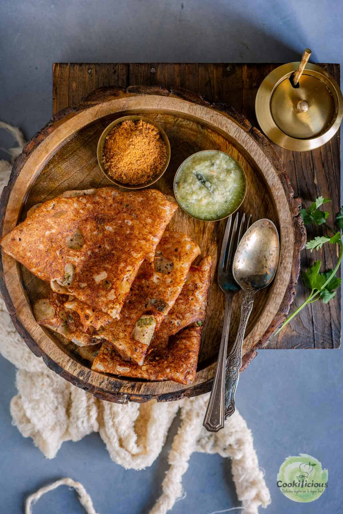 3 folded Onion Rava Dosa served in a plate with chutneys