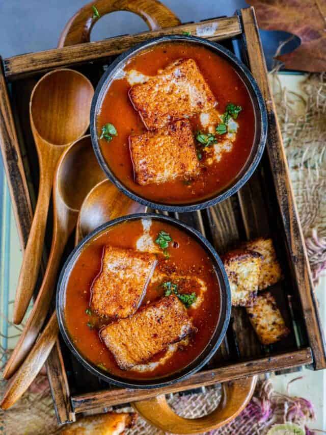 2 bowls of vegan tomato soup served in a wooden tray