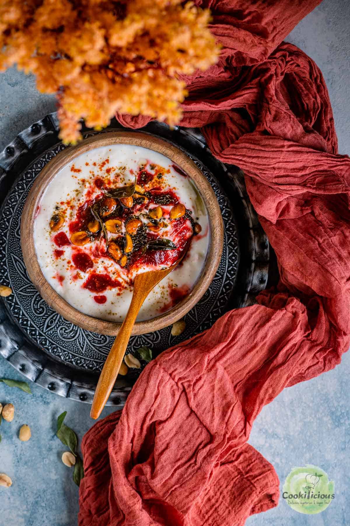 Vegan Beetroot Peanuts Raita served in a bowl with a spoon in it