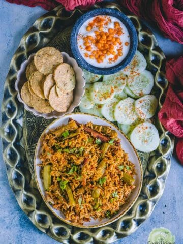 Tendli Masala Bhaat served in a platter along with salad, raita and papad