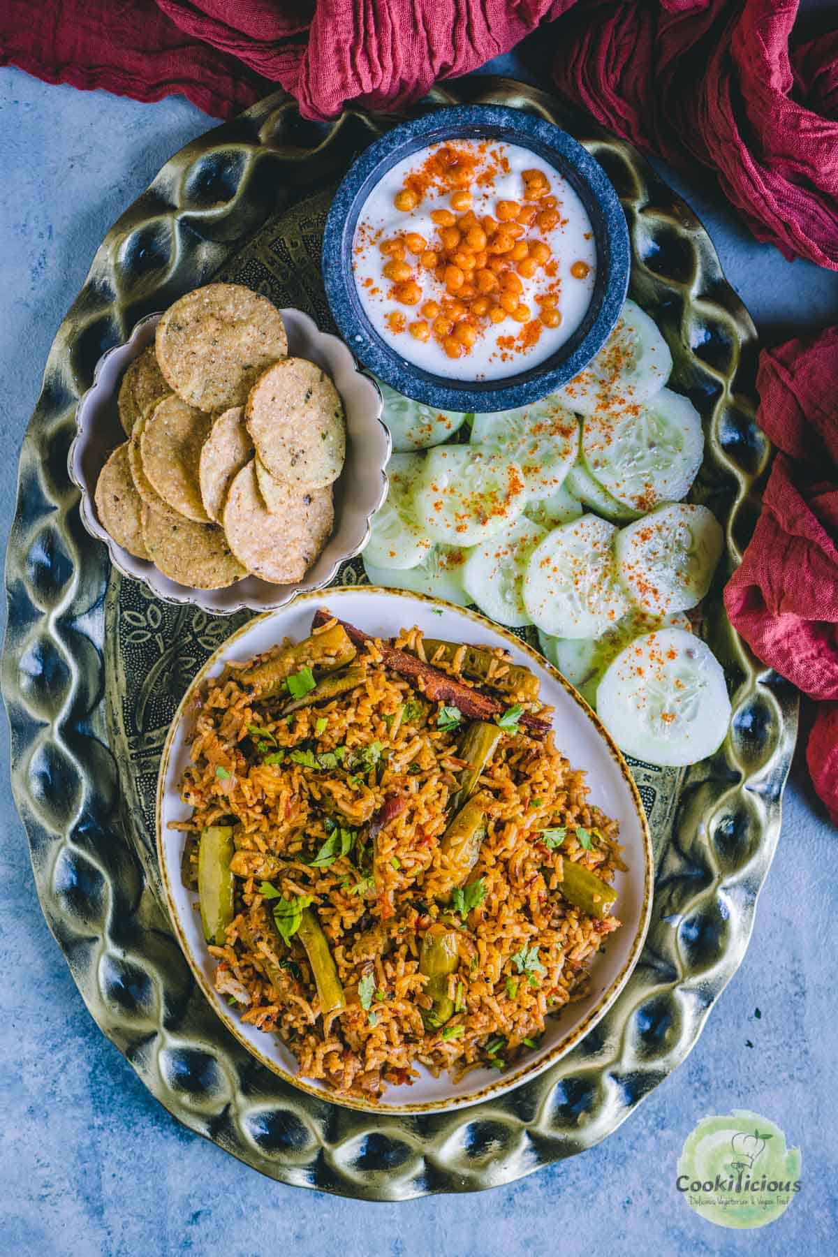 Tendli Masala Bhaat served in a platter along with salad, raita and papad