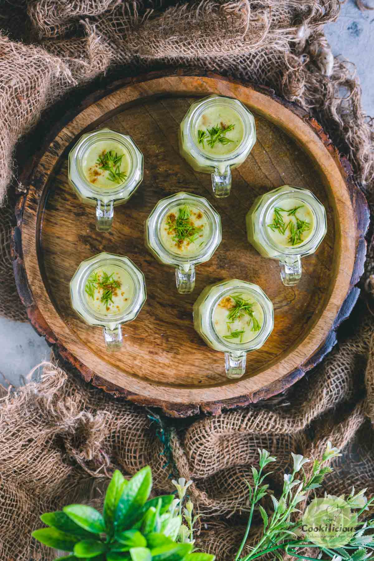 a wooden tray filled with cucumber soup shot glasses