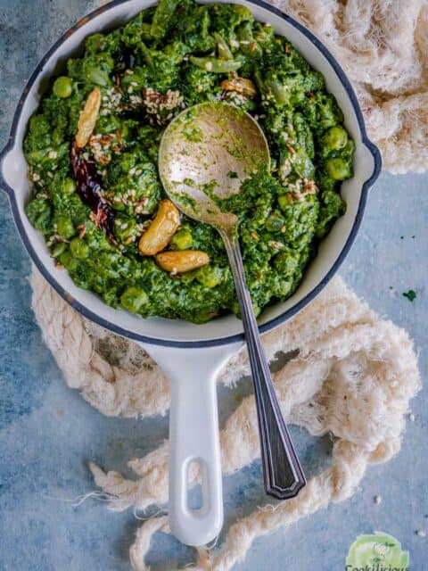 a spoon resting on a bowl of Lasooni Matar Palak