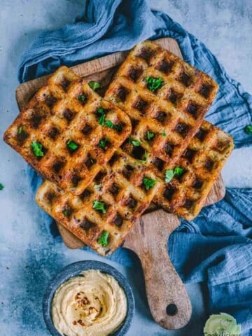 4 Potato Hummus Waffles served on a wooden tray with a bowl of hummus on the side