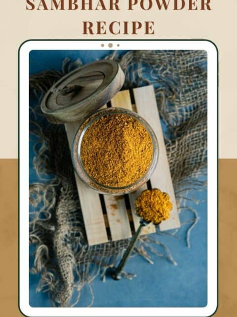Sambhar Powder stored in a jar with a spoon next to it and text at the top and bottom