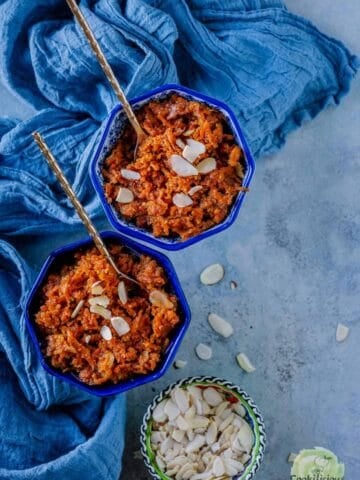 2 bowls of Instant Pot Vegan Carrot Halwa with a bowl of sliced almonds on the side