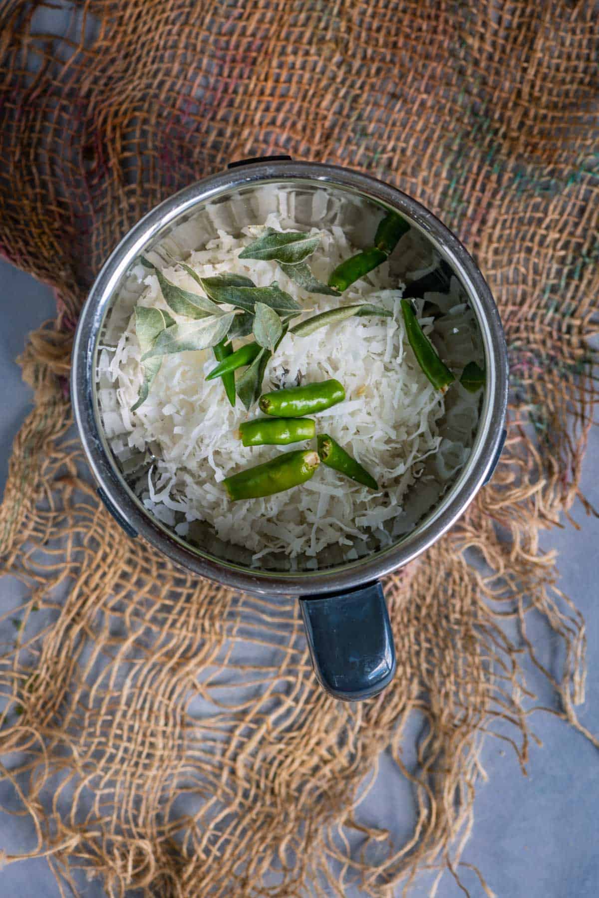 Shredded coconut, curry leaves, and green chillies in a blender jar.