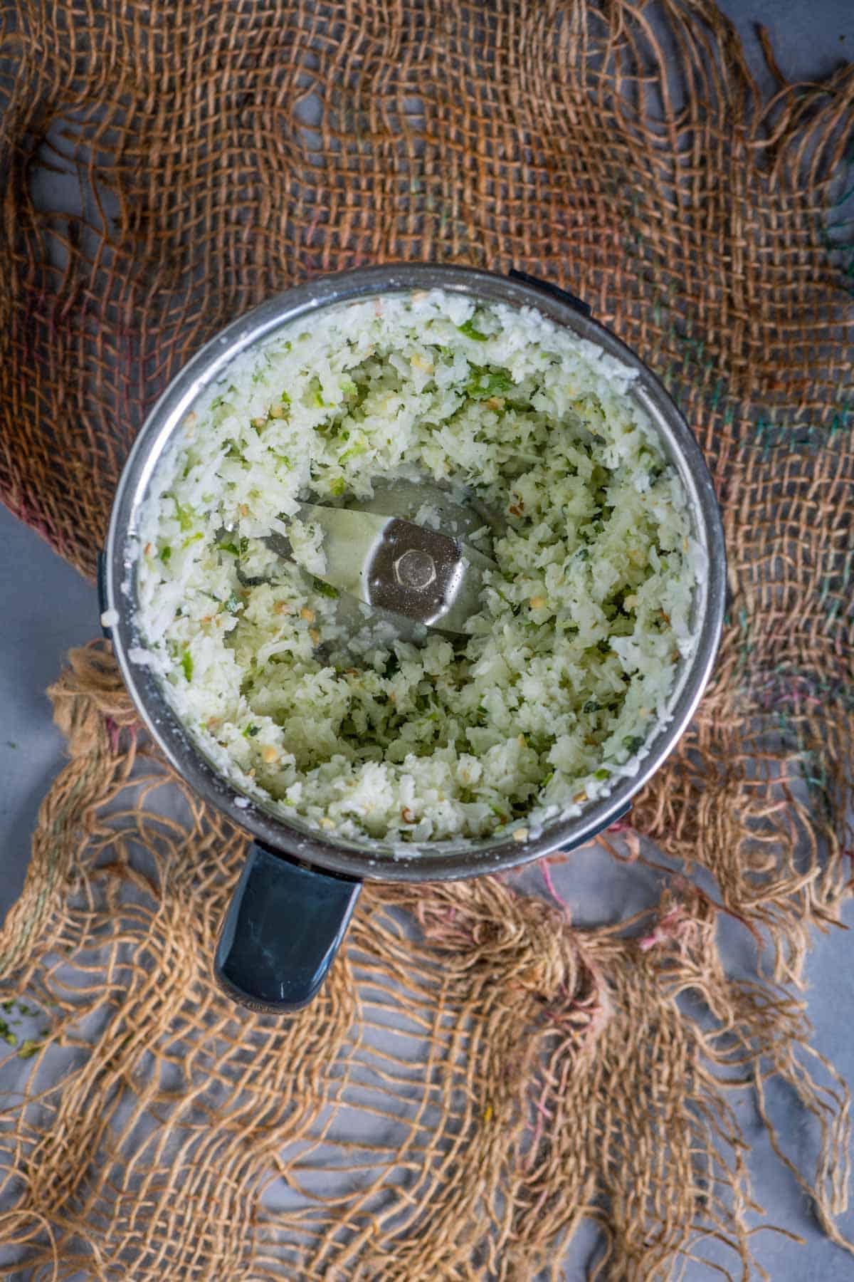 Coarsely ground coconut paste in a blender jar.