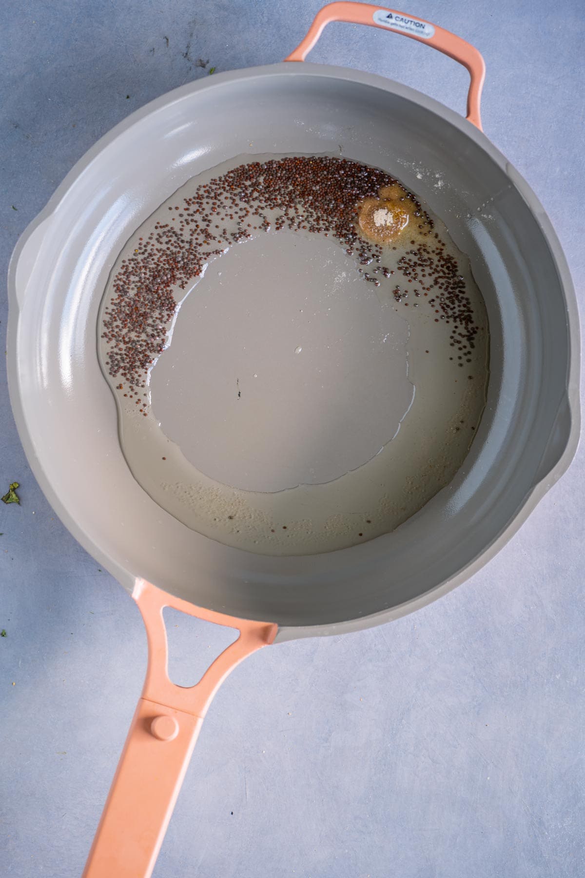 Mustard seeds and asafoetida tempering in oil in a pan.