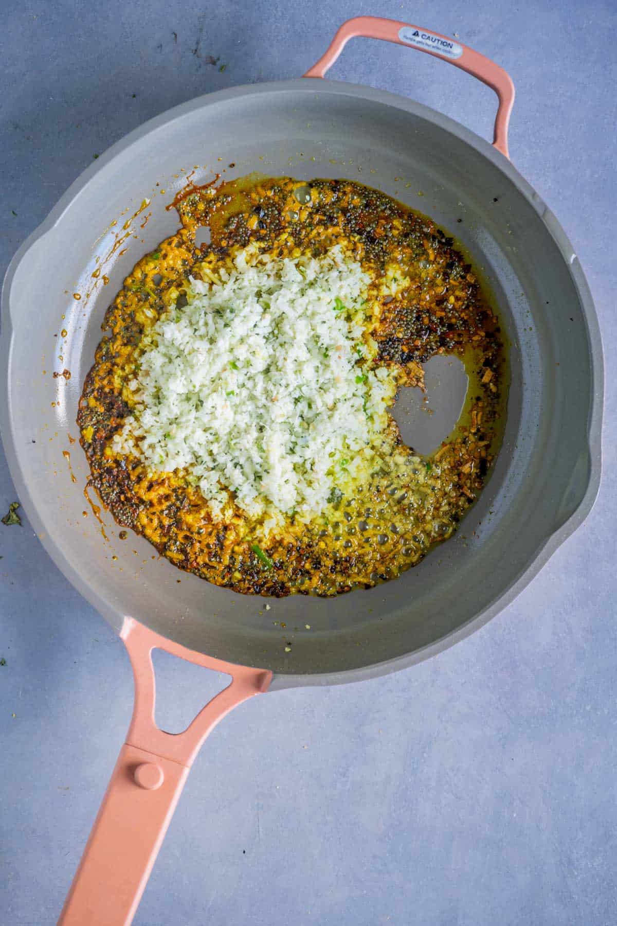 Ground coconut paste added to the tempered spices in a pan.