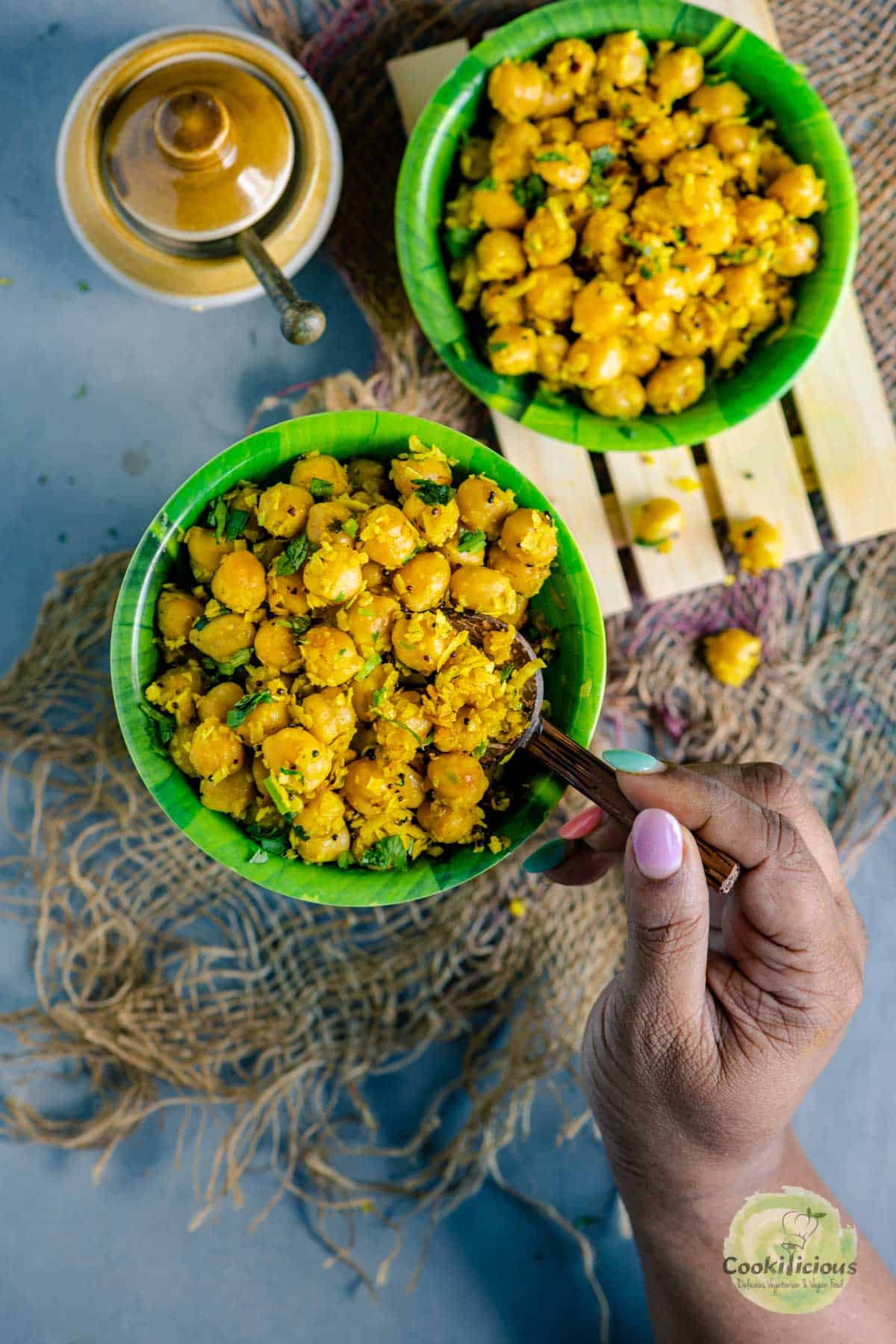 a hand digging into a bowl of chickpea sundal holding a spoon