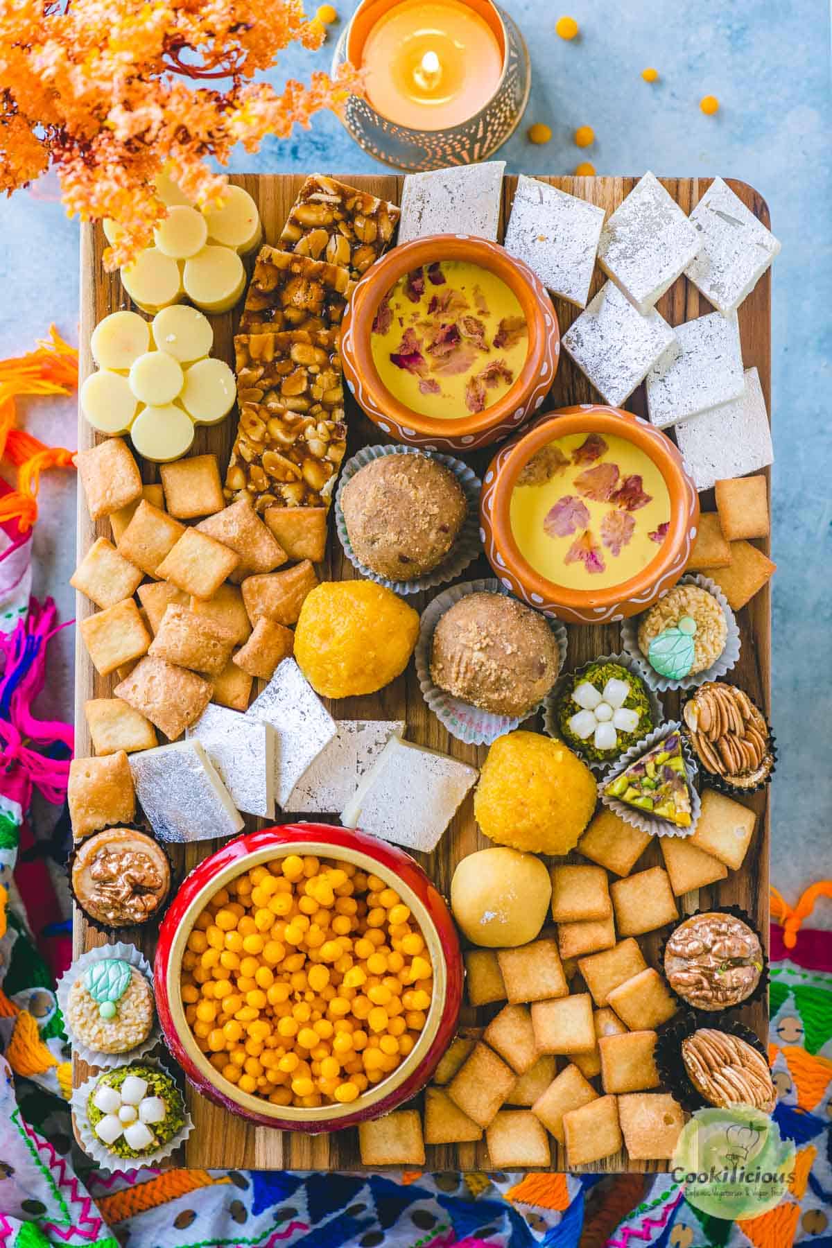 a variety of Indian desserts served on a wooden platter