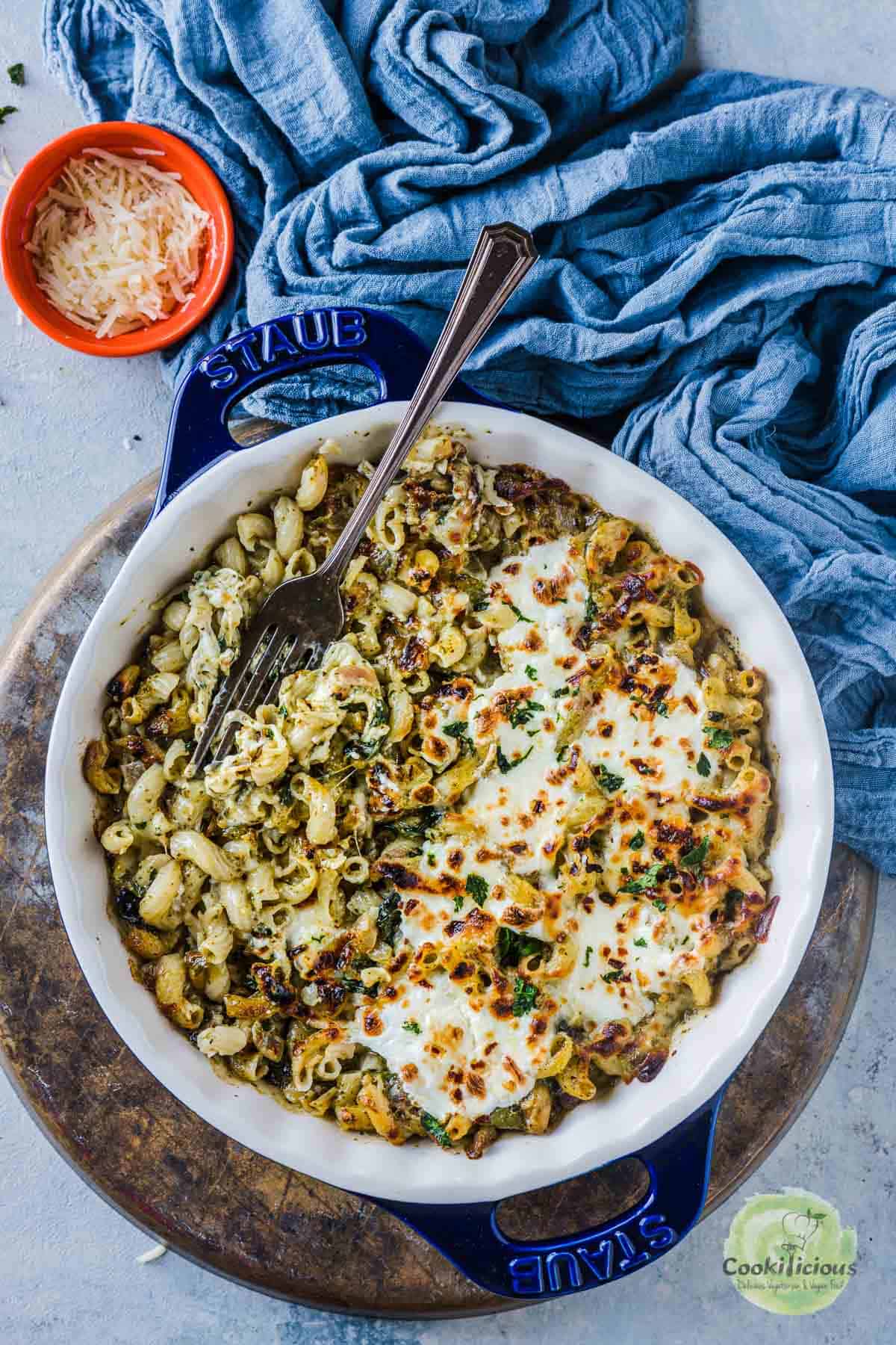 Creamy Pesto Pasta Bake served in a casserole with a fork in it