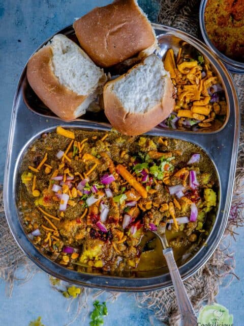 a plate served with misal, pav and chopped onions