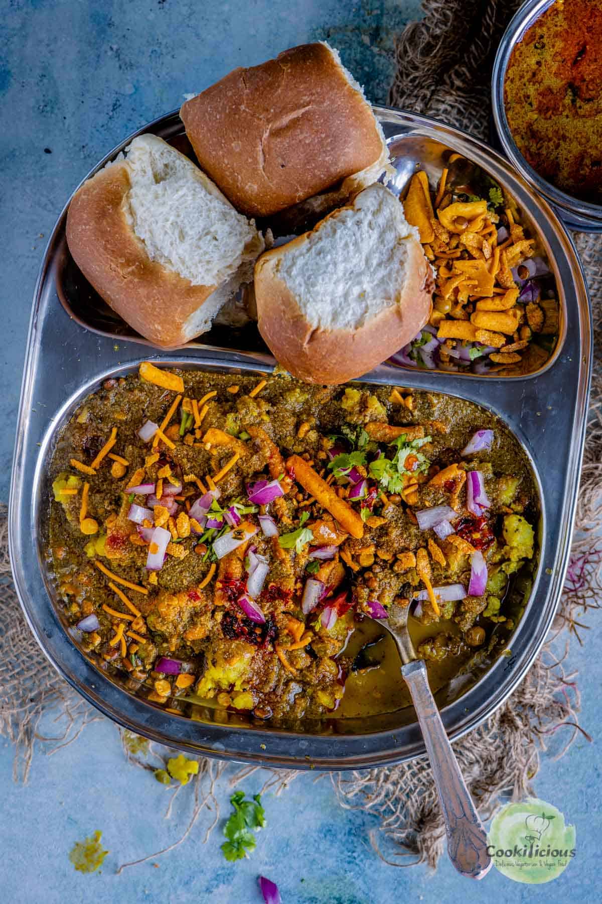 a plate served with misal, pav and chopped onions