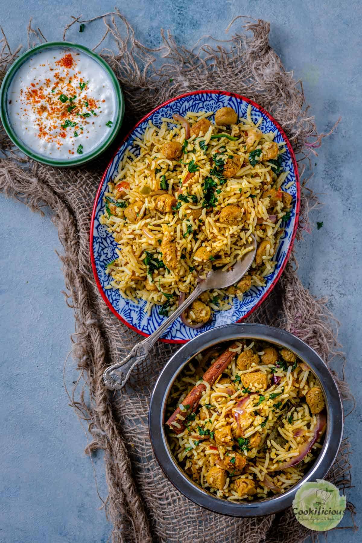 Soya Chunks Pulao served in an oval platter with a bowl of the same on the side along with raita