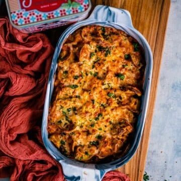 Baked Tortellini Casserole placed on a wooden board with a pasta tin on the side