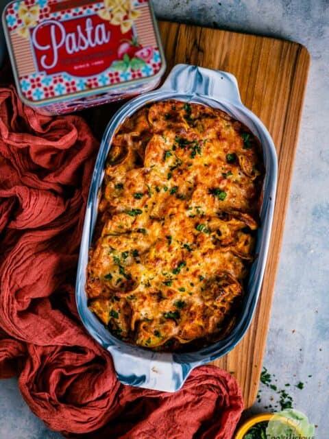Baked Tortellini Casserole placed on a wooden board with a pasta tin on the side