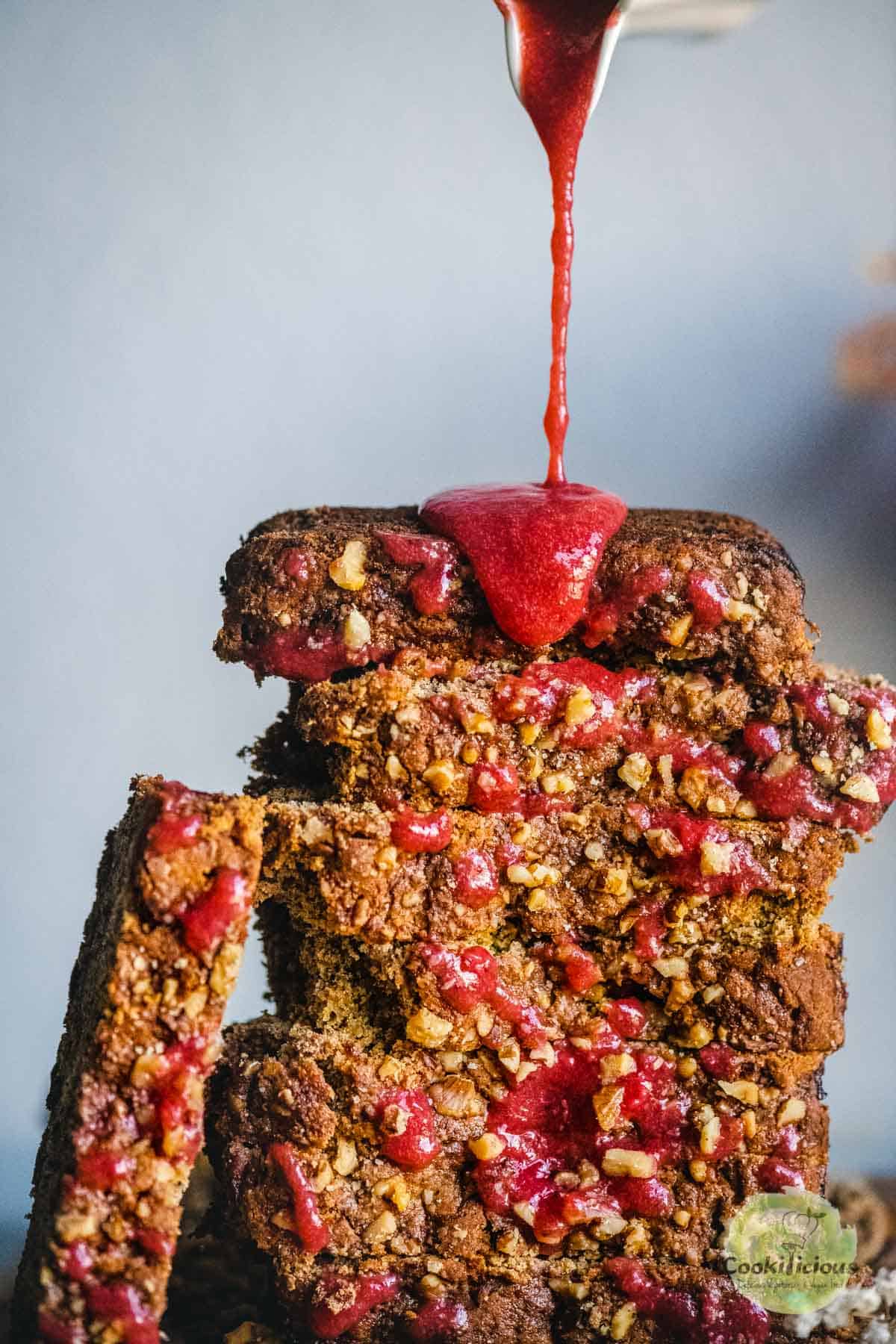 strawberry syrup being poured over a stack of Vegan Gluten-free Banana Strawberry Bread
