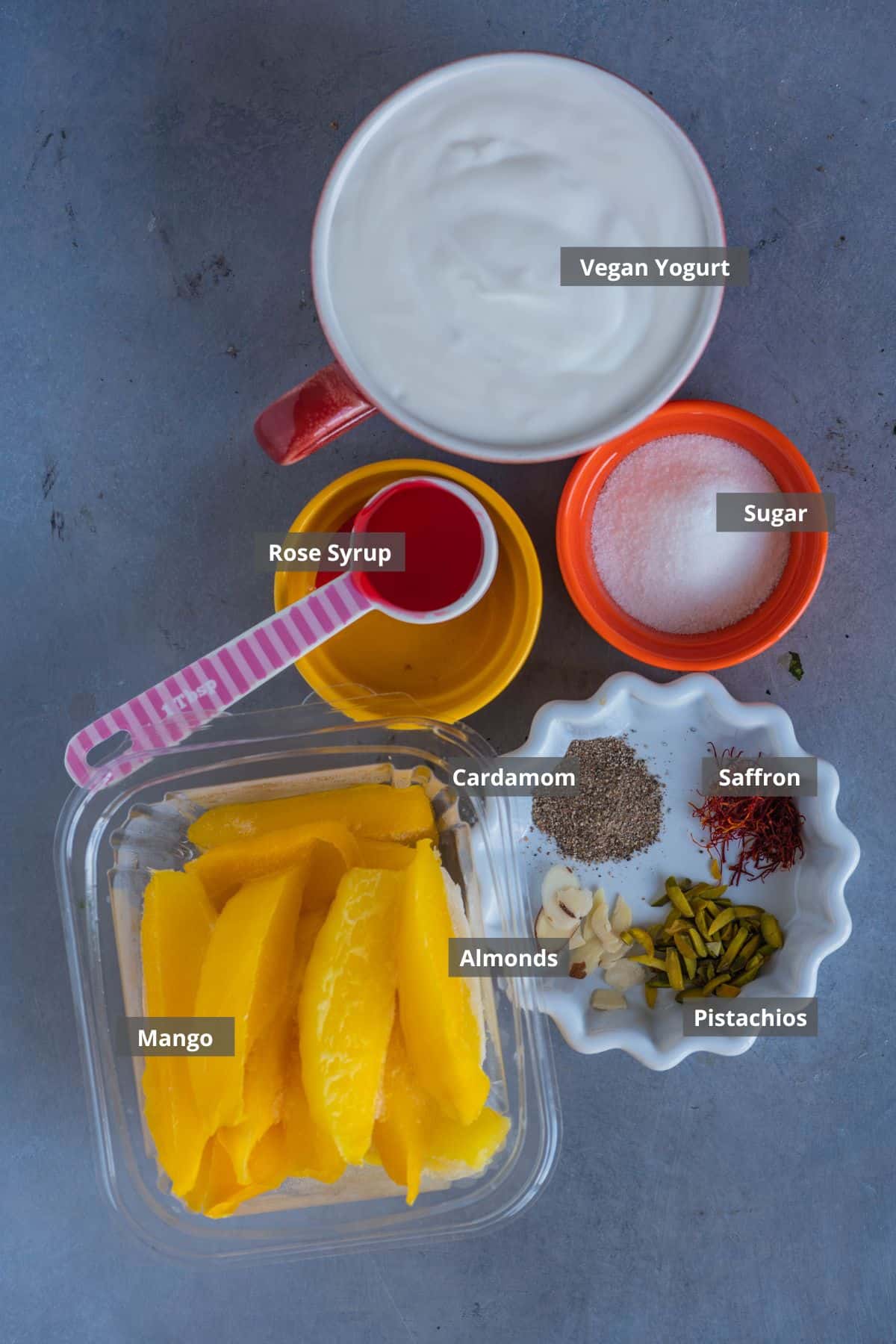 all the ingredients needed to make sweet vegan mango rose lassi with labels on them.