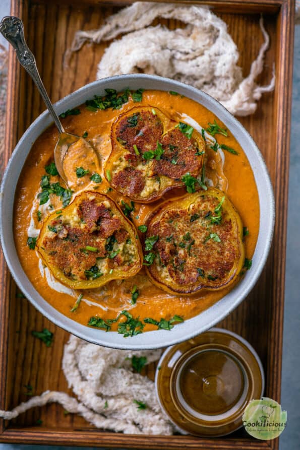 Paneer Masala Stuffed Peppers In Creamy Tomato Gravy served on a wooden tray.