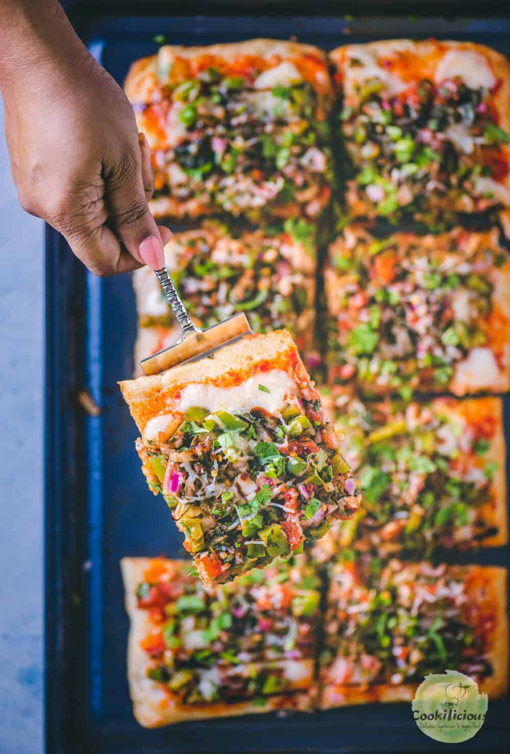 a hand holding a slice of Easy Tomato Bruschetta Pizza.