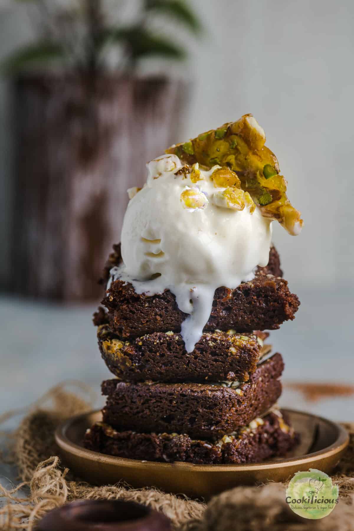 Eggless chocolate brownies placed one on top of the other with a scoop of vanilla ice cream on top.