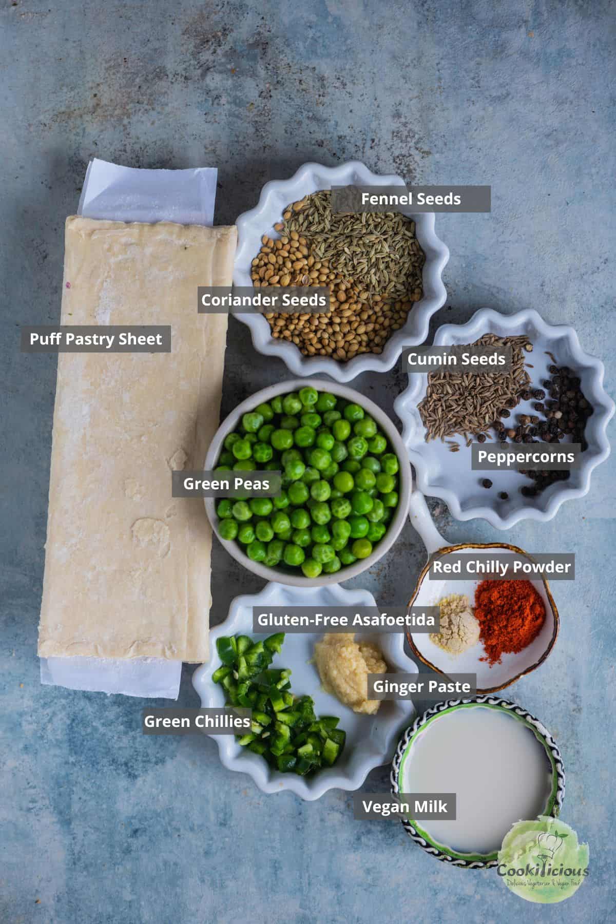 All the ingredients needed to make Puff Pastry Pinwheels With Matar Kachori Filling placed on a table with labels on them.
