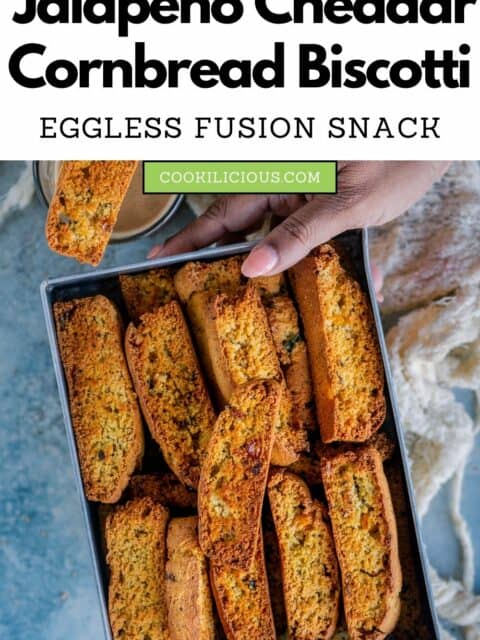 one hand holding a tray full of Eggless Jalapeno Cheddar Cornbread Biscotti and text at the top.