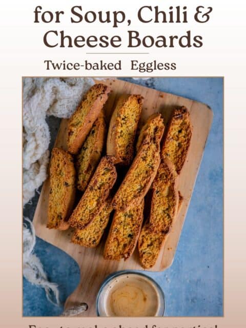 Crunchy cornbread biscotti on a wooden board with a glass of coffee, with text reading “Cornbread Biscotti for Soup, Chili & Cheese Boards – Twice-baked, Eggless – Easy to make ahead for parties!
