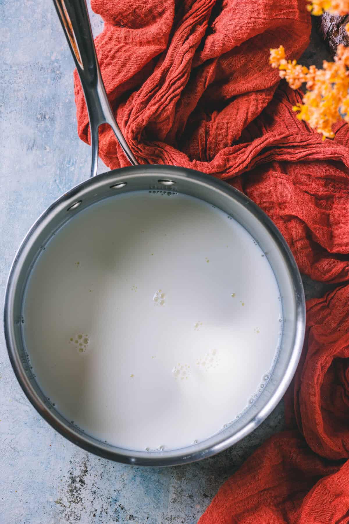 Milk being poured into a pot to make haldi ka doodh.