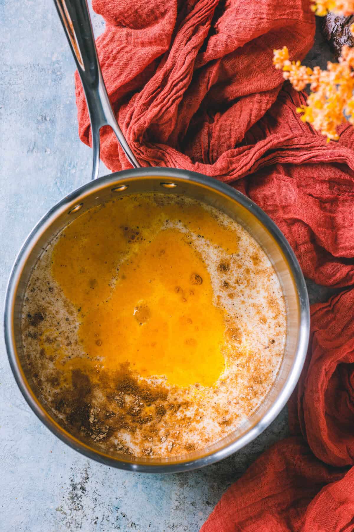 Turmeric powder and warming spices added to milk in a pot to make golden milk.