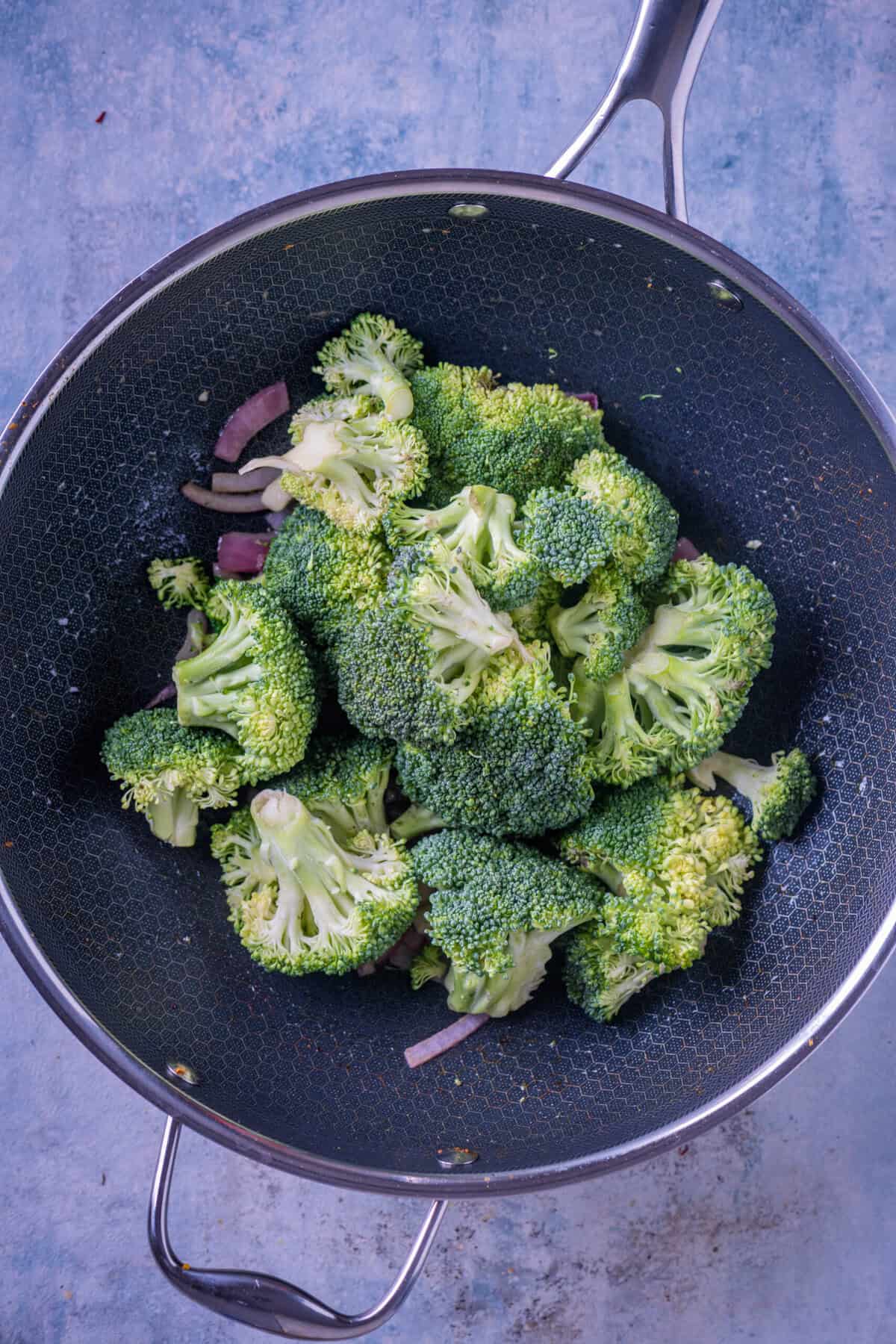 Adding fresh broccoli florets to the pan for vegan broccoli soup.