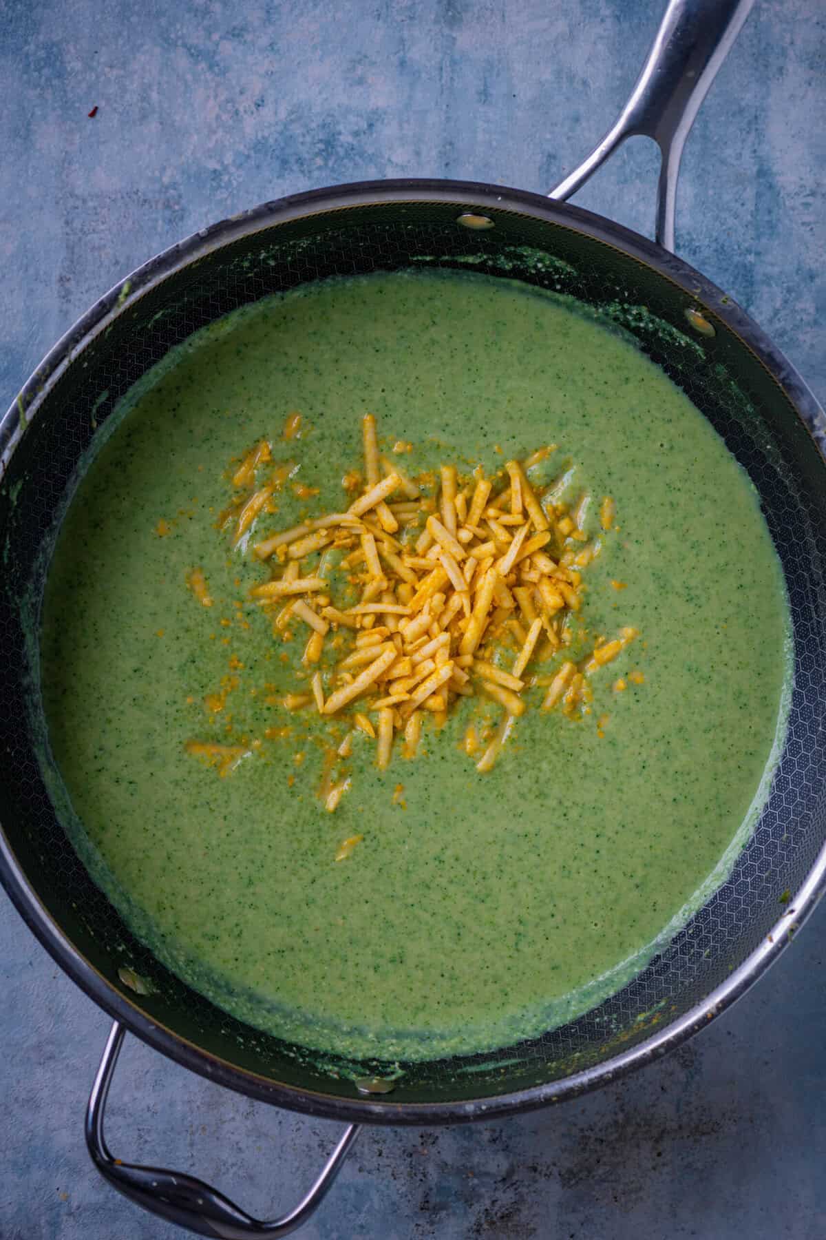 Melting vegan cheddar cheese into broccoli soup.