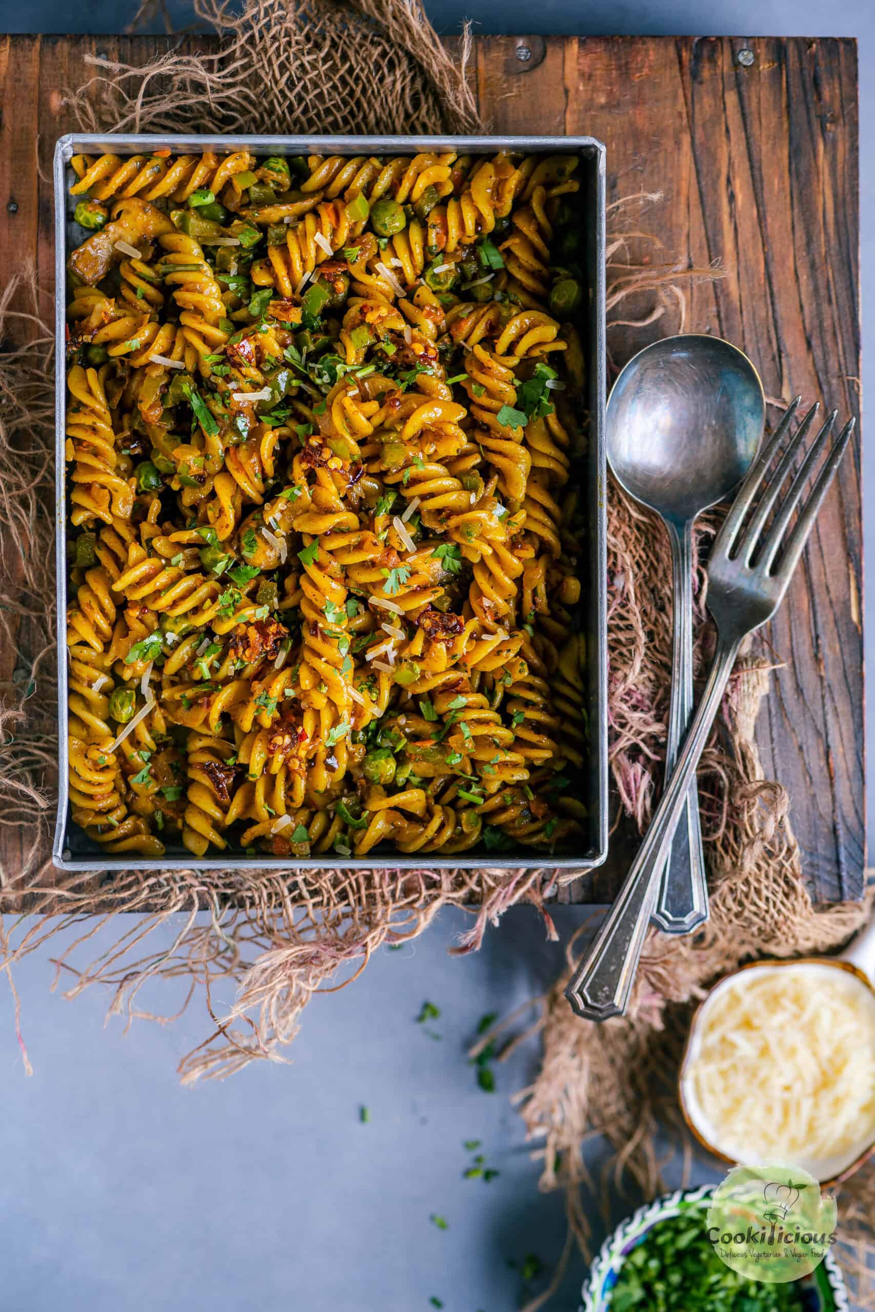 Indian masala curry pasta in a serving dish with a spoon and fork on the side.