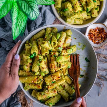 a set of hands of holding a plate filled with Italian pasta with broccoli.