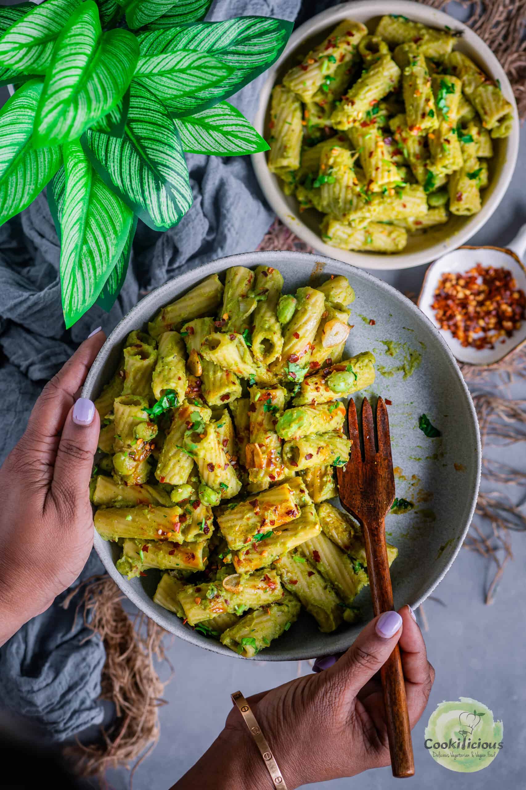 a set of hands of holding a plate filled with Italian pasta with broccoli.