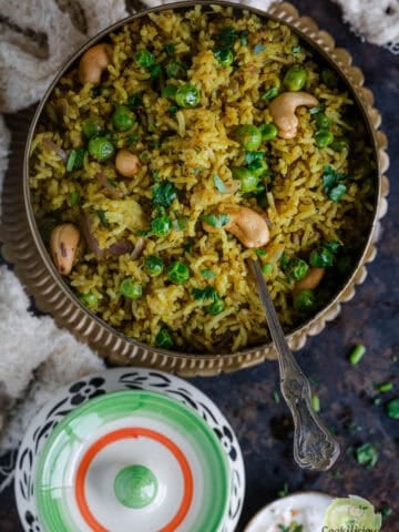 Matar pulao served in a round bowl with a spoon in it,