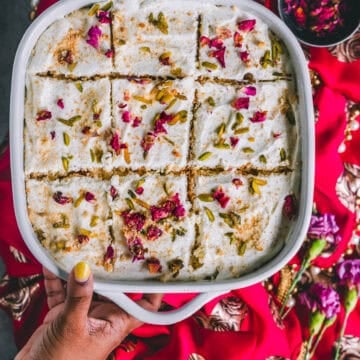 a hand holding a casserole of rasmalai cake.