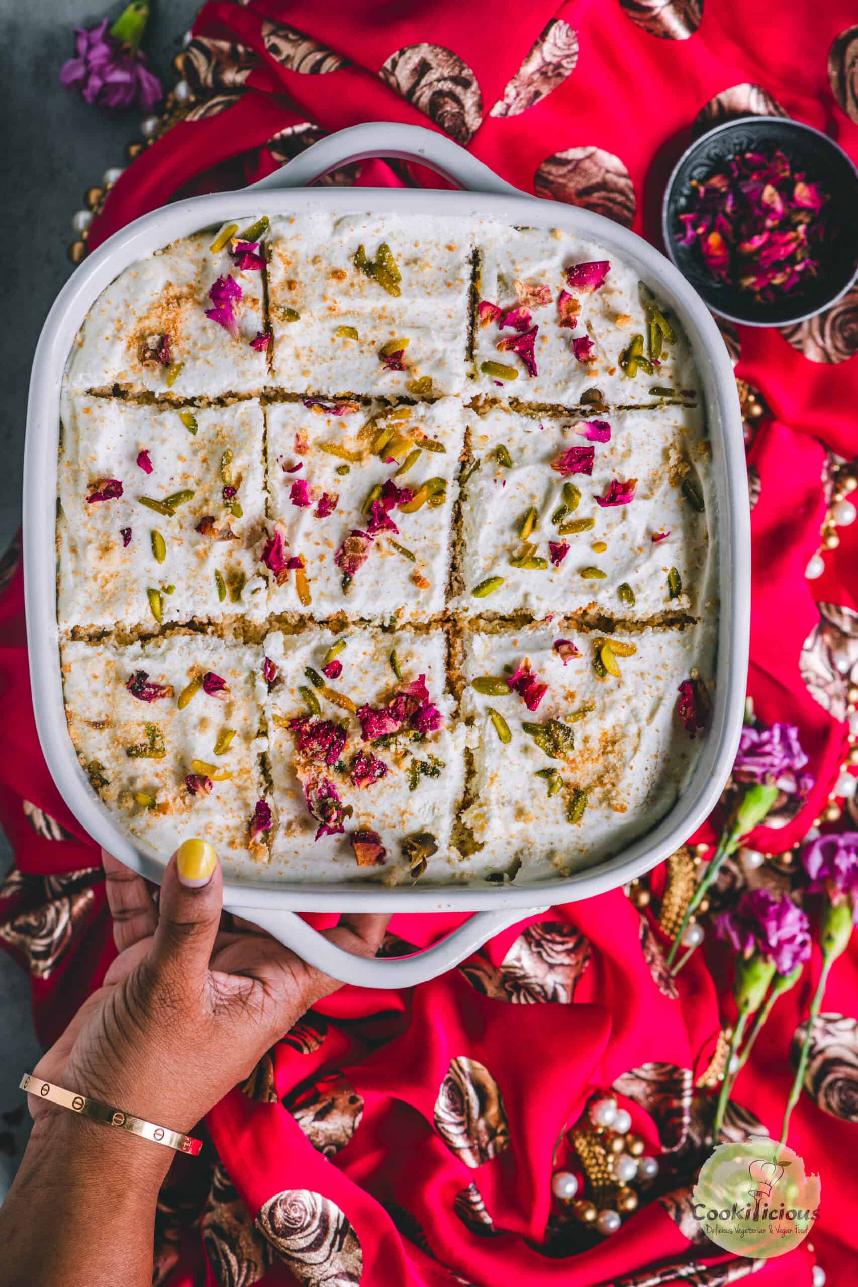 a hand holding a casserole of rasmalai cake.