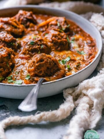 Vegan kofta curry served in a bowl with a spoon in it.