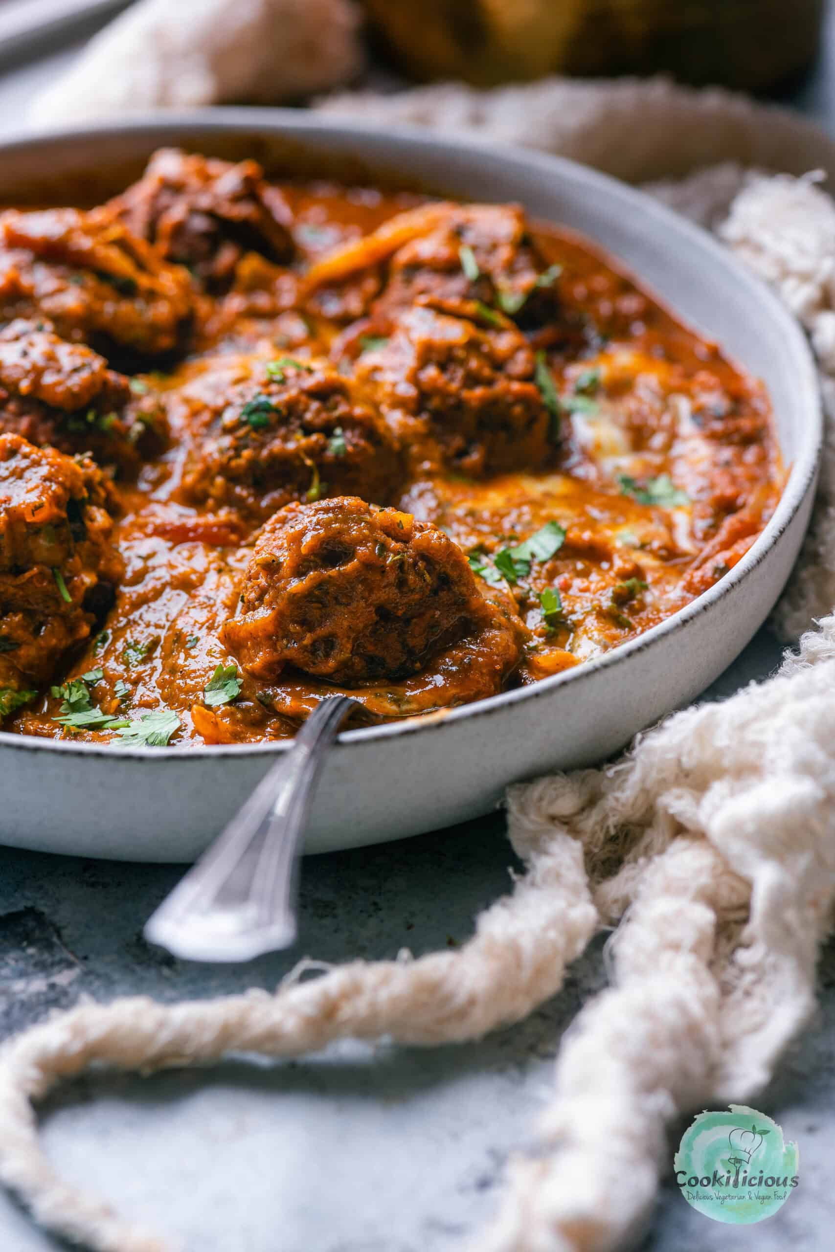 Vegan kofta curry served in a bowl with a spoon in it.